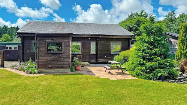 A wooden cabin with a porch, a small garden, and a clear blue sky. - 2 bedroom accommodation in Ellerbeck (Ellerbeck)
