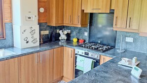 A kitchen with wooden cabinets, a gas stove, a built-in oven, and a refrigerator. - 2 bedroom accommodation in Ellerbeck (Ellerbeck)