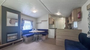 Un intérieur de camping-car compact comprenant un coin cuisine, un espace salon avec une table et des chaises, et un grand miroir.