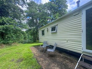 A mobile home with a patio area, two chairs, and a small table. - 2 bedroom accommodation in Hevingham (Hevingham)
