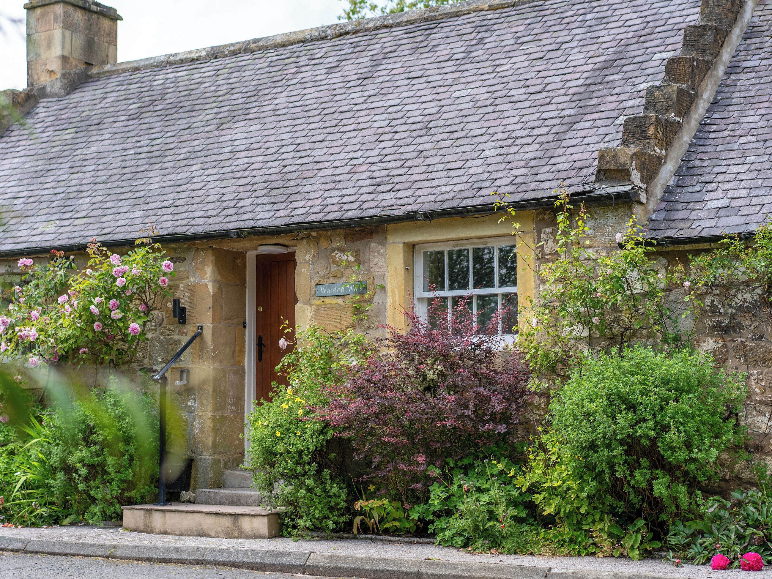 Un bâtiment en pierre avec un toit en pente, une porte en bois et une petite fenêtre.
