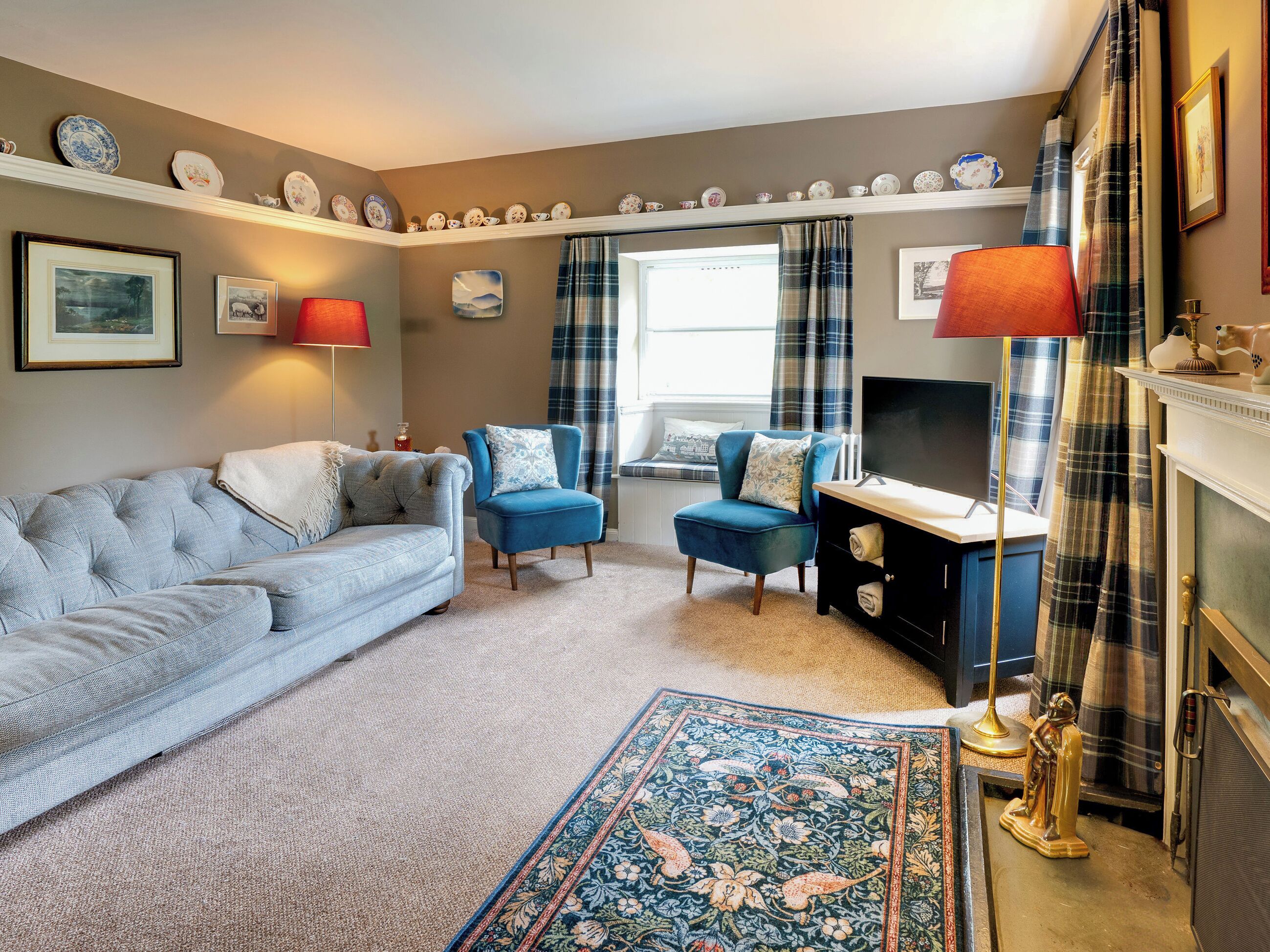 A living room with a sofa, armchair, fireplace, and a decorative rug.