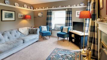 A living room with a sofa, armchair, fireplace, and a decorative rug.