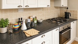 A kitchen with white cabinets, a gas stove, a coffee maker, and various kitchen items on the counter. - 2 bedroom accommodation in Norwich (Norwich)