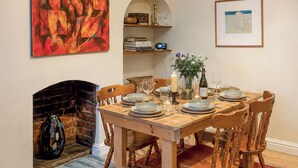 A dining room with a brick fireplace, wooden table, and chairs. - 2 bedroom accommodation in Norwich (Norwich)