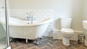 Ein Badezimmer mit einer freistehenden Badewanne, einer Toilette und einem Mülleimer.