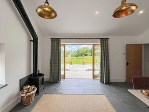 A spacious room with a large sliding glass door leading to a patio, a fireplace, and two pendant lights.