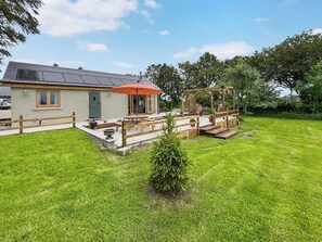 Ein Haus mit Terrasse, kleinem Garten und einer Holzterrasse.