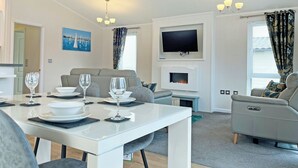 Una sala de estar moderna con comedor, televisor de pantalla plana, chimenea y sofá.