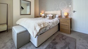 Une chambre à coucher comprenant un lit, des lampes de chevet, une table de chevet, un miroir, une armoire et un banc.