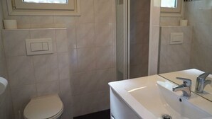 Ein Badezimmer mit Toilette, Waschbecken, Dusche und Spiegel.