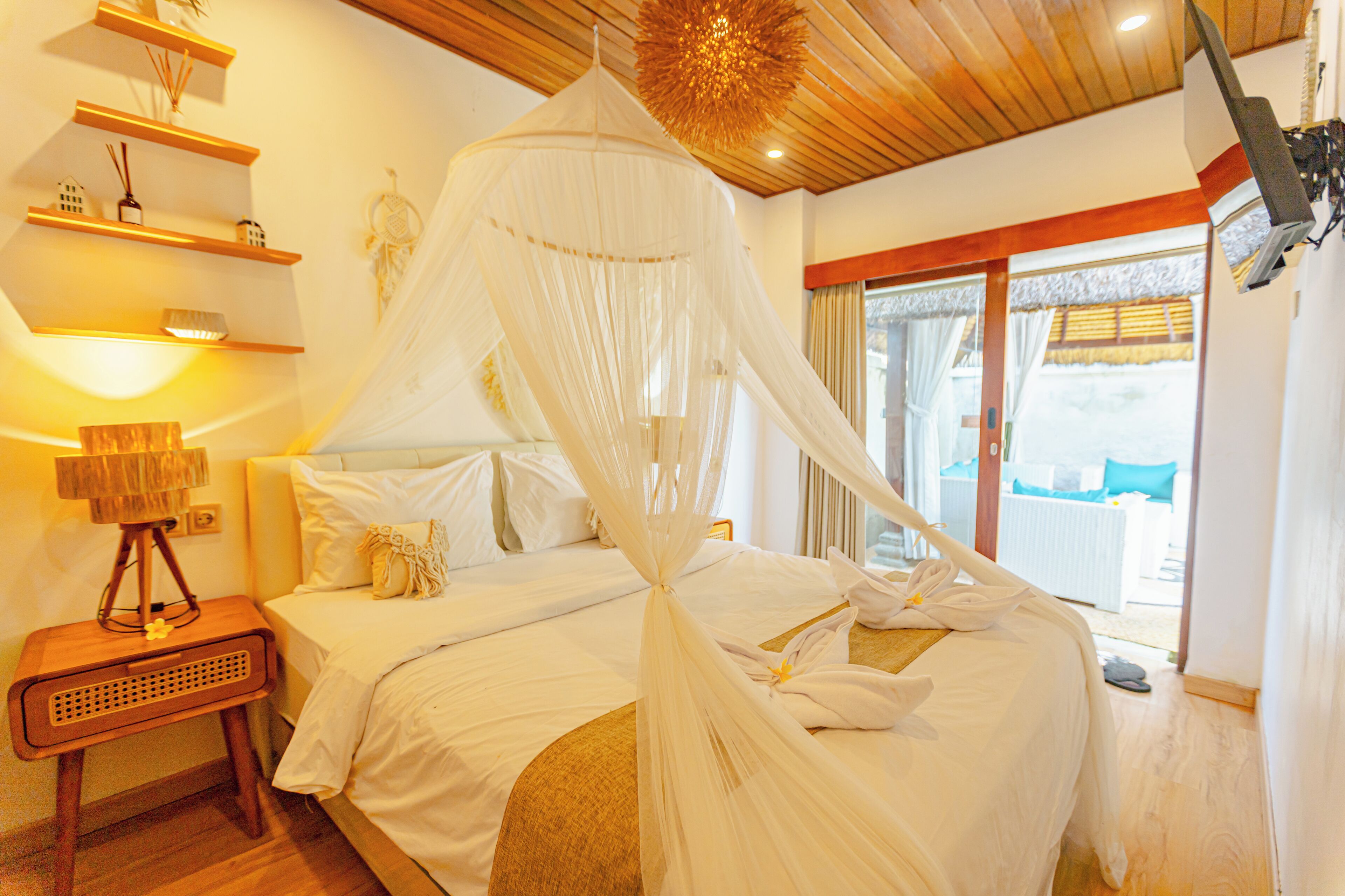 A bedroom with a canopy bed, wooden headboard, bedside tables, and a view of the outdoors.