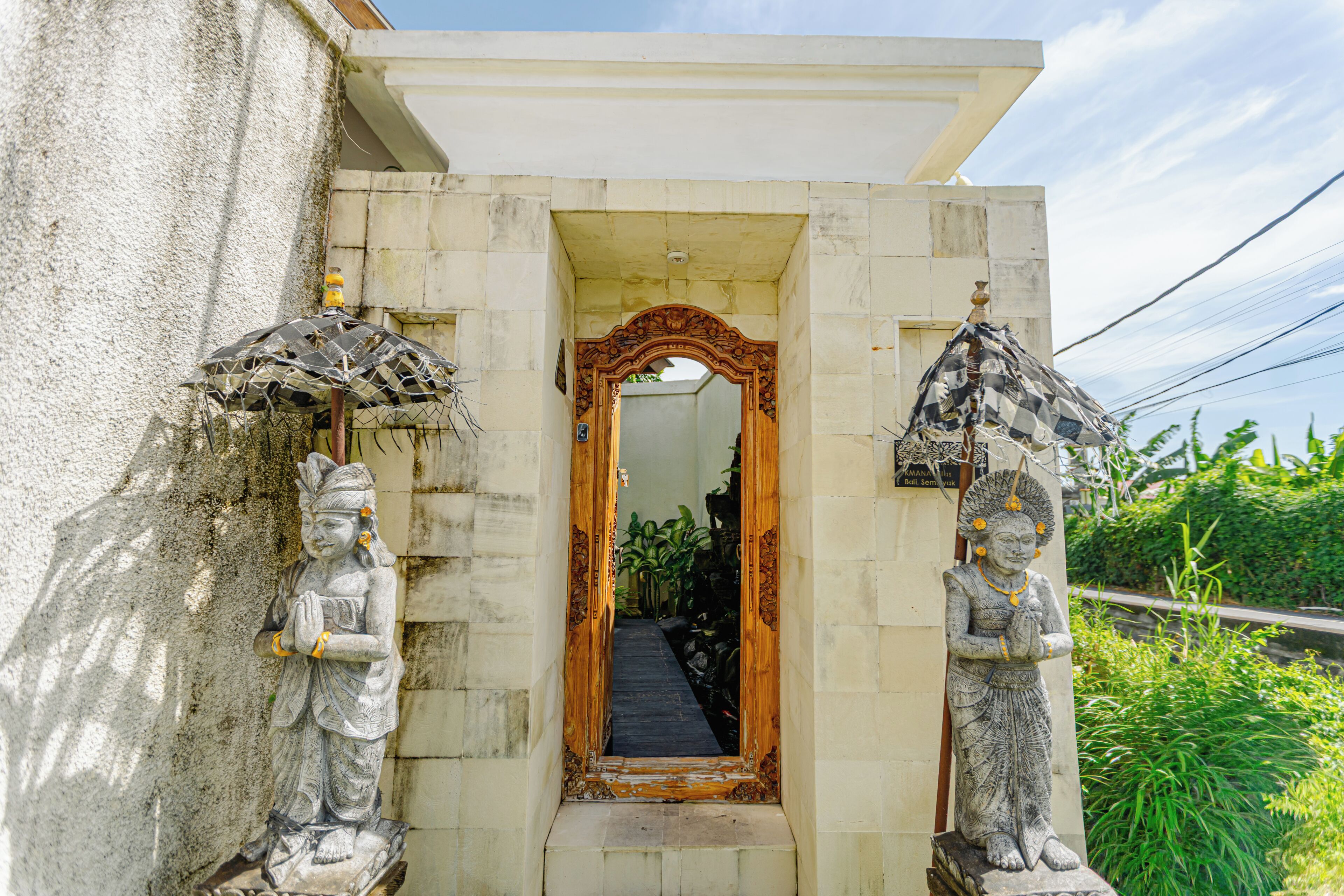 A doorway with a mirror, flanked by statues and a small shrine.
