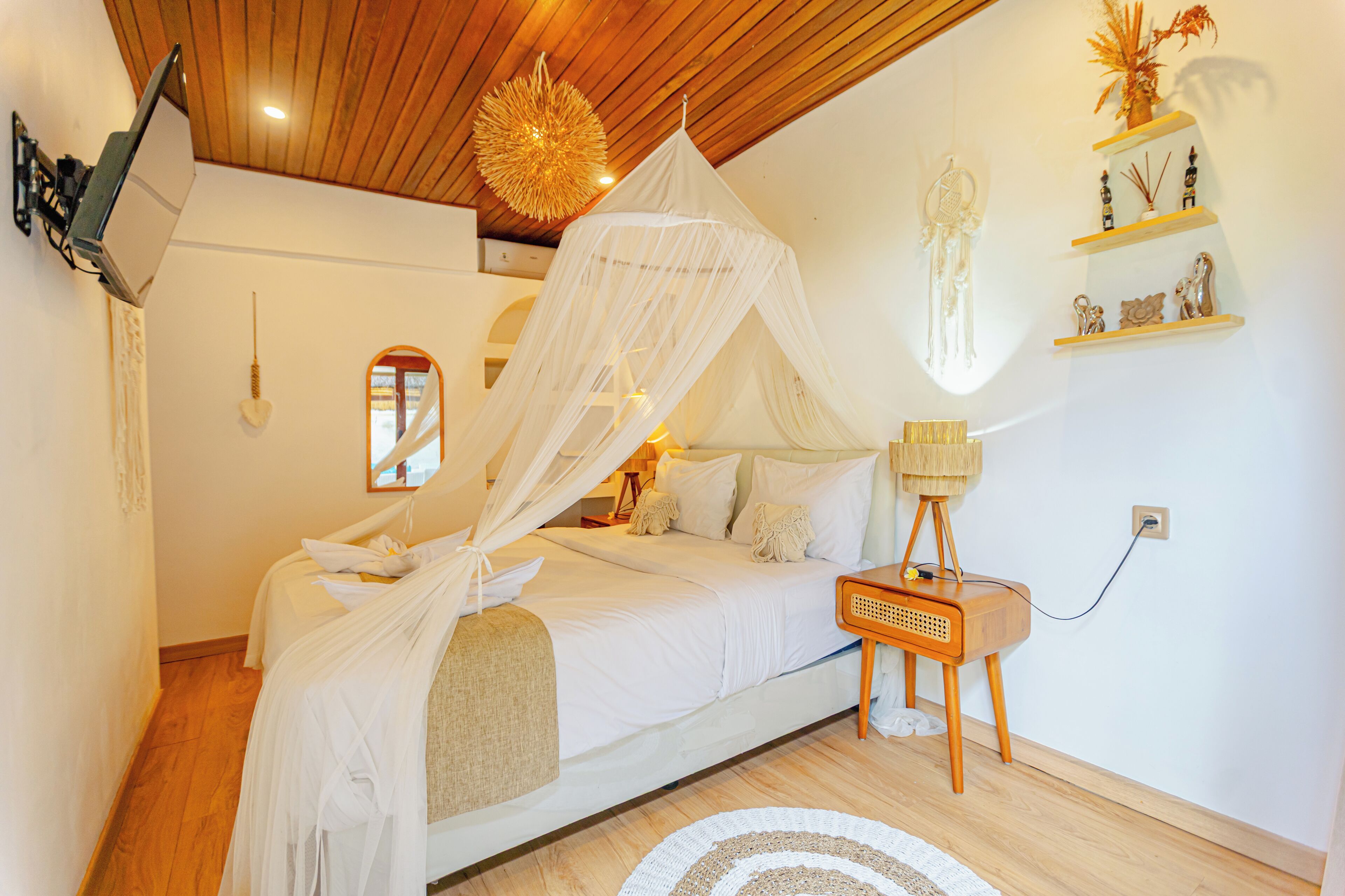 Ein Schlafzimmer mit Himmelbett, Nachttisch, Lampe, Wandregal und einem Spiegel.