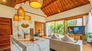 Una sala de estar moderna con una isla de mármol, suelo de madera, un sofá y un televisor.