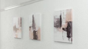 Three abstract paintings on a textured white wall.