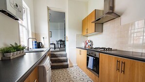 A kitchen with wooden cabinets, a gas stove, a built-in oven, and a patterned floor. - Entire rental unit in Tyne and Wear, United Kingdom (Gateshead)