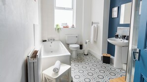 A bathroom with a bathtub, toilet, sink, and patterned floor tiles. - Entire rental unit in Tyne and Wear, United Kingdom (Gateshead)