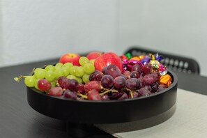 Un bol de fruita variada sobre una taula, amb un comandament a distància al fons.