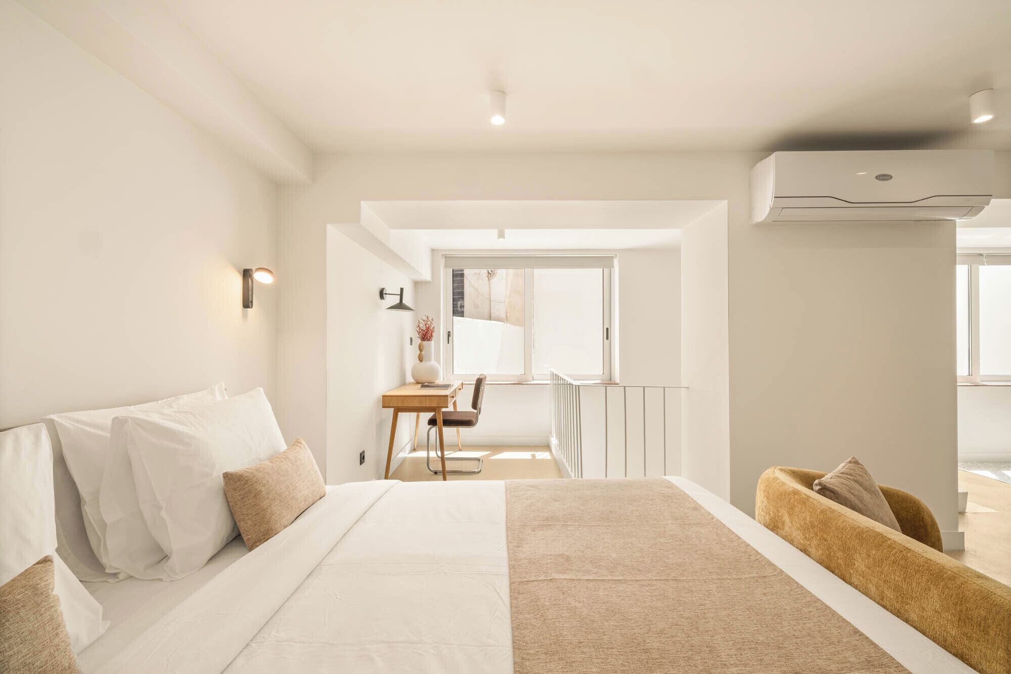 A hotel room with a bed, a desk, and a chair. There is a window with a view of the outside.
