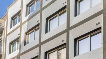 Un edificio de varios pisos con un estilo arquitectónico moderno, que presenta una fachada enrejada con ventanas y balcones uniformemente distribuidos.