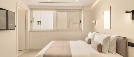 Une chambre moderne avec un grand lit, un téléviseur à écran plat, une fenêtre avec vue et une table de chevet avec une lampe.