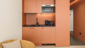 A compact kitchenette with a built-in oven, a sink, and a coffee maker. - Grid II by Zoia Living (Athens)