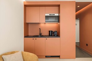 A compact kitchenette with a built-in oven, a sink, and a coffee maker.