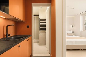Quarto de hotel moderno com banheiro, cama e escada que leva a outro andar.