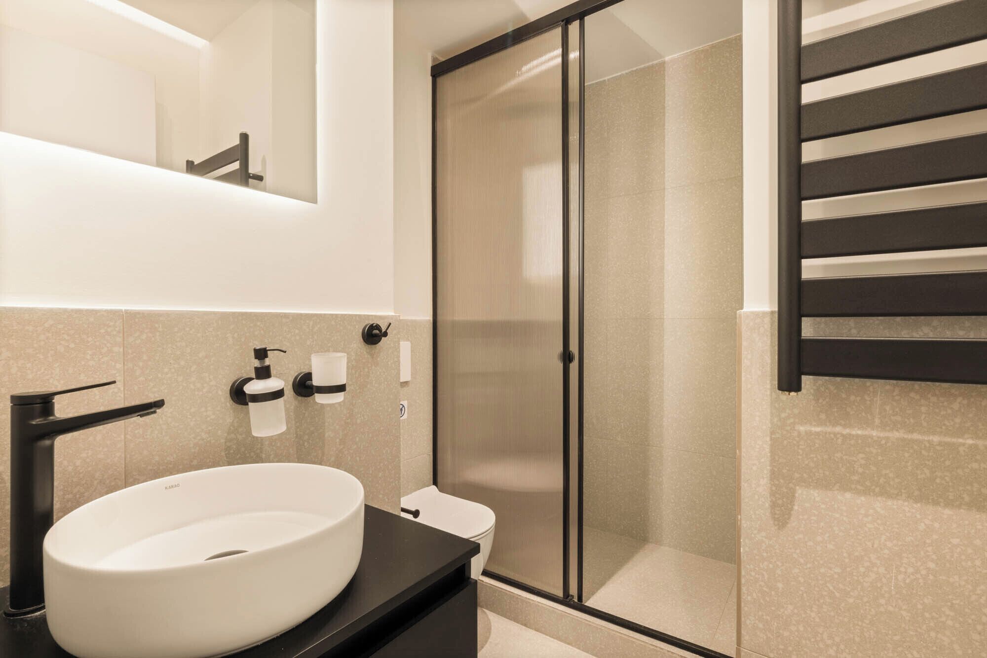 Un baño moderno con un lavabo blanco grande, un inodoro y una cabina de ducha de vidrio.