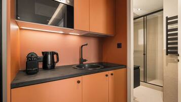 A compact kitchenette with a built-in oven, a coffee maker, and a sink.
