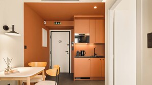 A compact kitchenette with a microwave, coffee maker, and cabinets. - Grid II by Zoia Living (Athens)