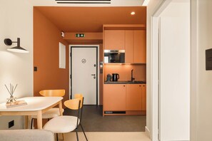 A compact kitchenette with a microwave, coffee maker, and cabinets.