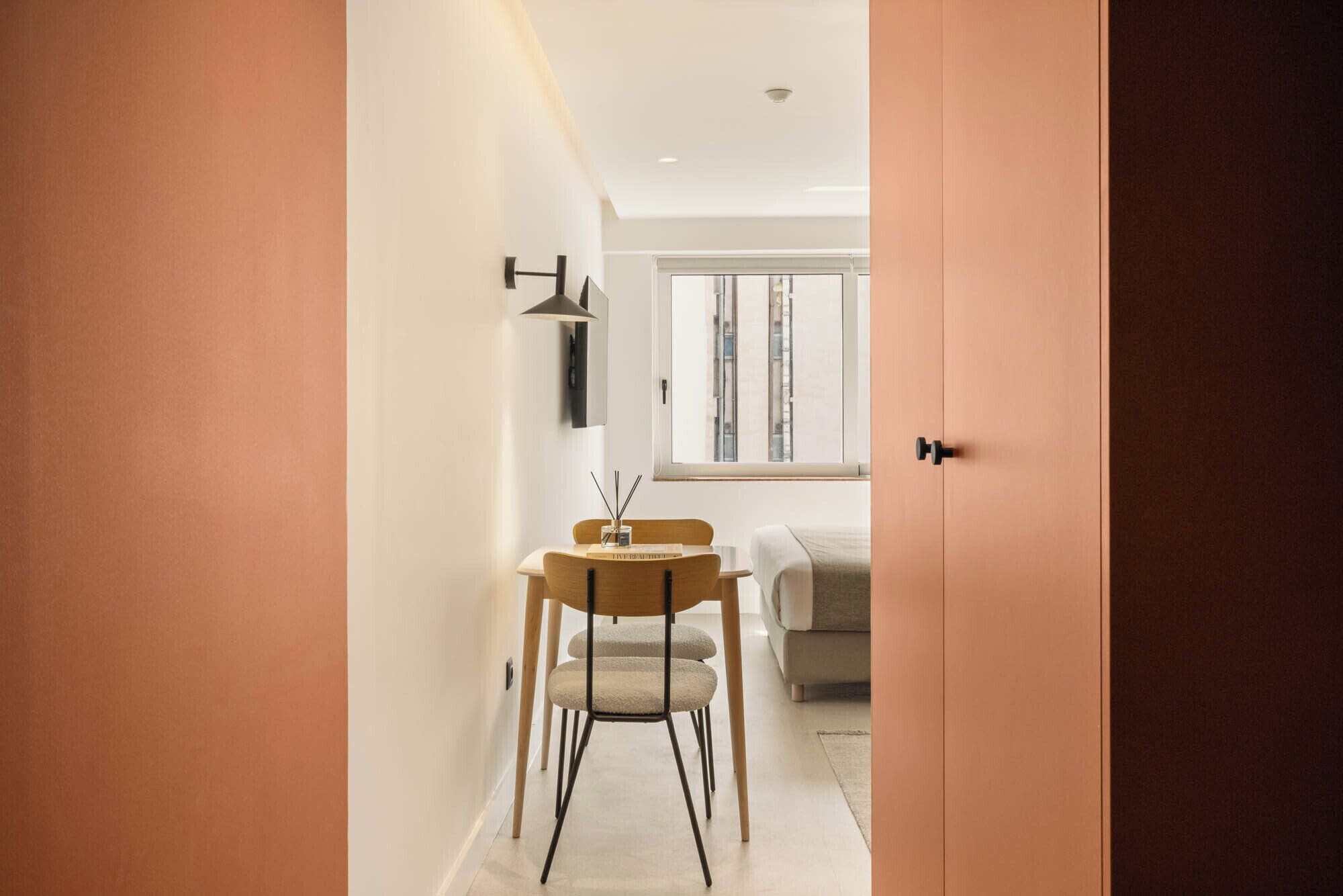 Un interior moderno con zona de comedor, sofá y ventana con vistas.