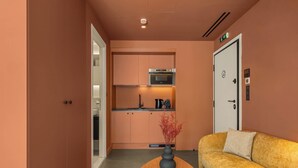 A compact hotel room with a kitchenette, a sofa, and a coffee table. - Grid by Zoia Living (Athens)