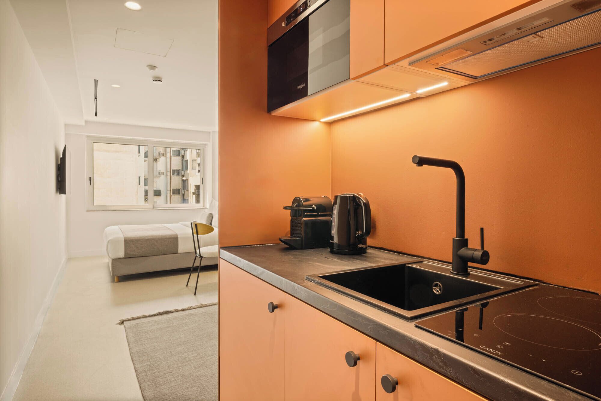A modern kitchen with a built-in microwave, a coffee maker, and a sink.