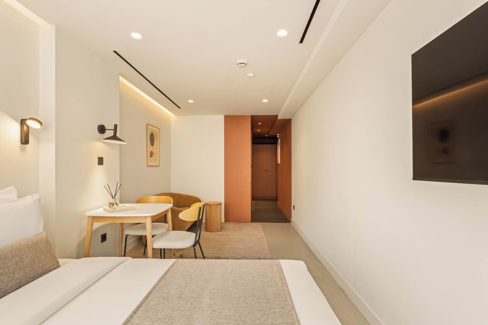 A modern hotel room with a bed, a desk, and a chair.