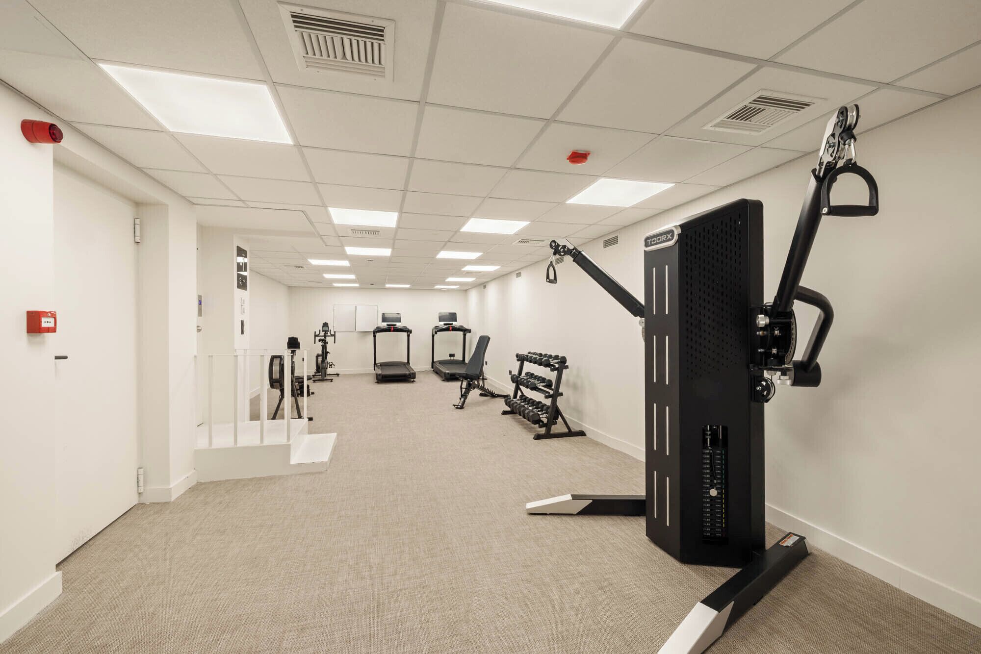 A gym with treadmills, weight machines, and a stationary bike.