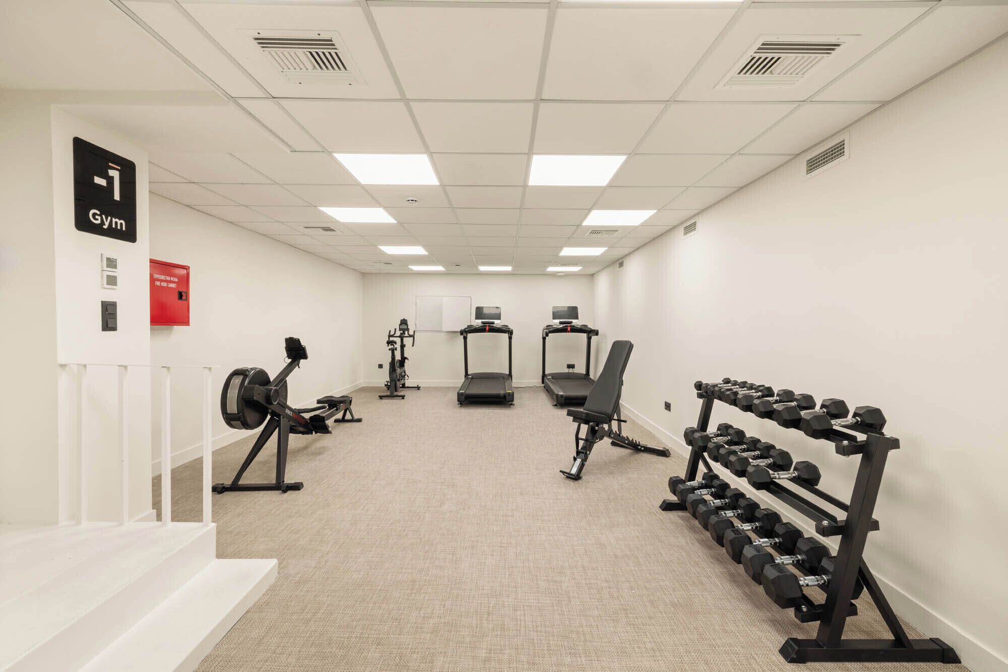Et fitnessrum med løbebånd, crosstrainer og bænkpresser.