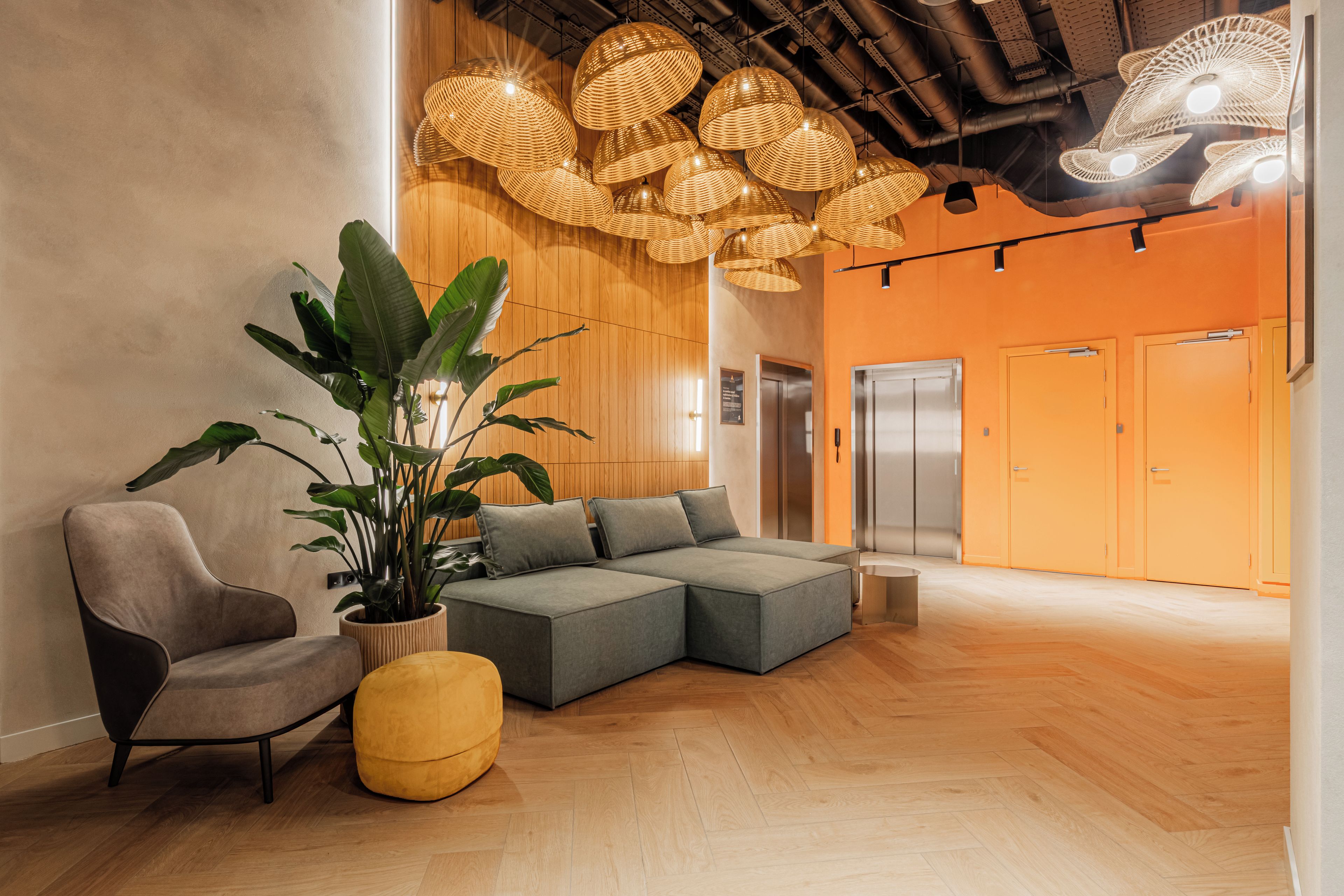 Un interior moderno con un sofá seccional, una planta en maceta y un taburete amarillo.