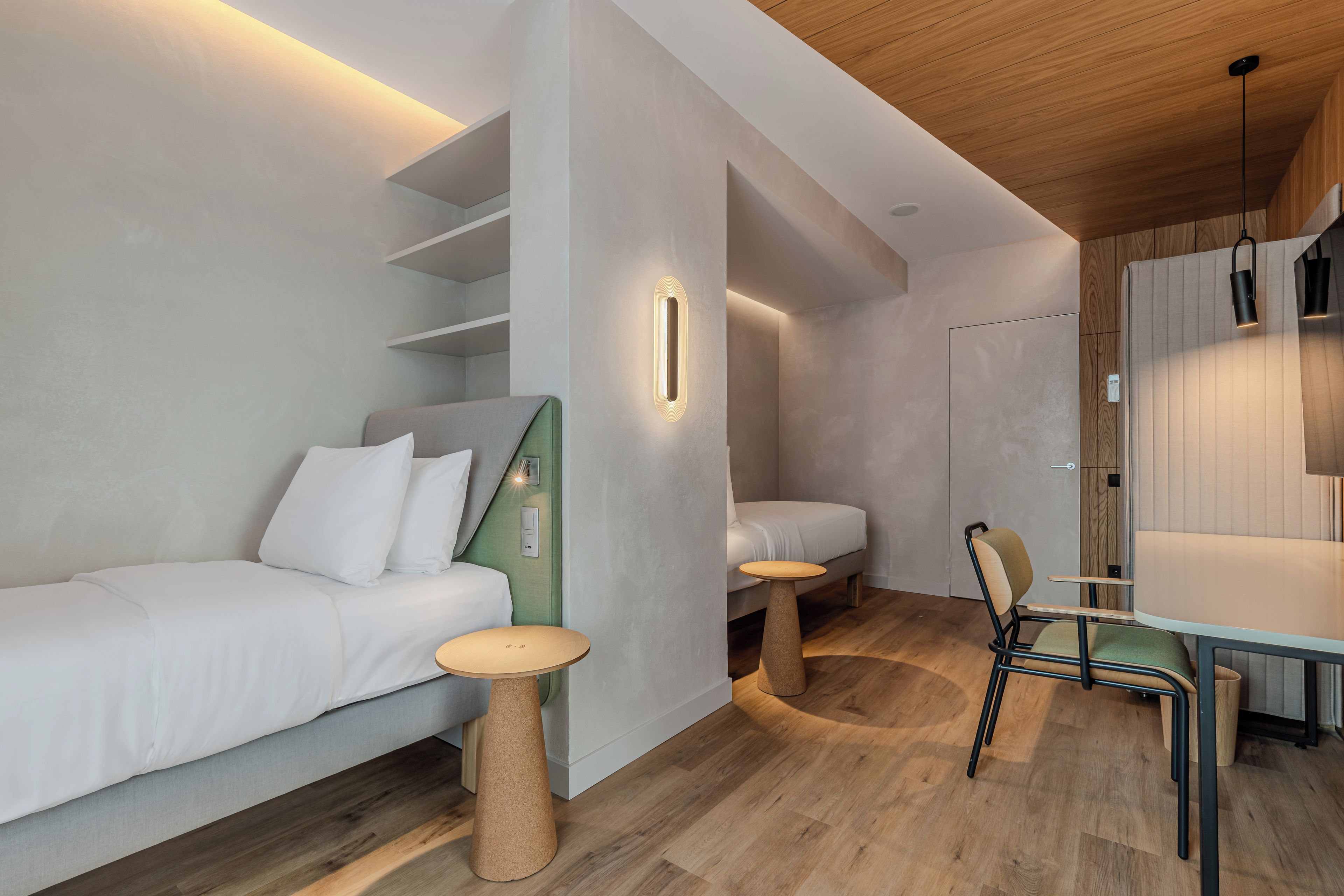 Un dormitorio moderno y bien iluminado con cama, mesitas de noche y una silla.