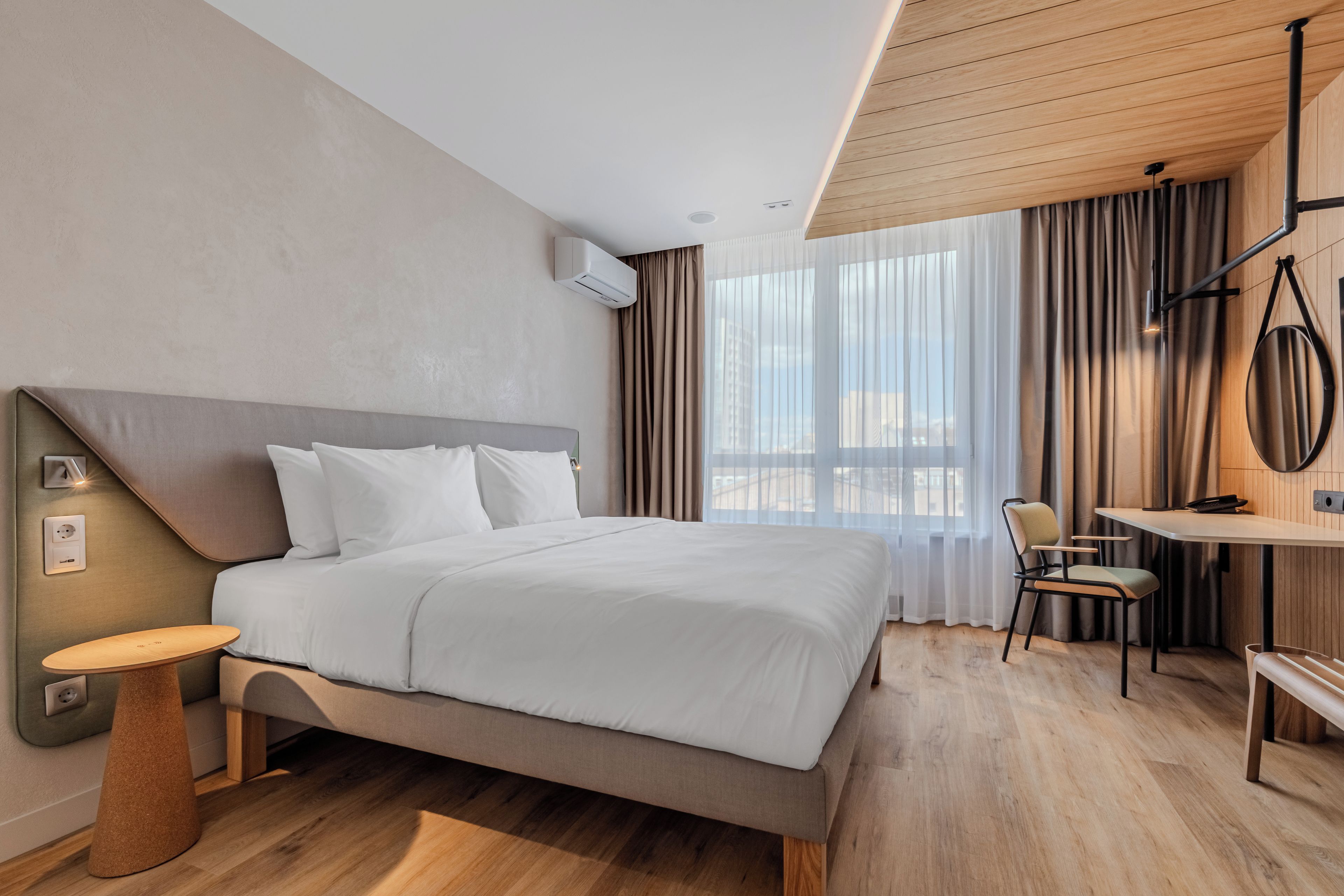 Une chambre d’hôtel moderne avec un grand lit, un bureau et une chaise.