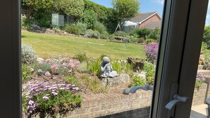 A garden with a statue, a brick wall, and a lawn. - Bungalow - Sleeps 2 - Parking (Newquay)