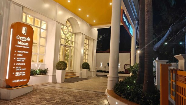 Entrada de hotel con un letrero de recepción, una escalera y un camino bien iluminado.