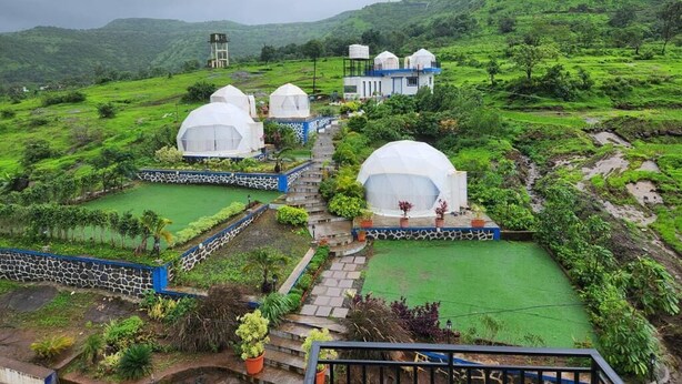 Un resort en la ladera con edificios de forma abovedada, jardines en terrazas y una torre de agua.