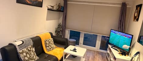 A living room with a sofa, coffee table, TV, and a guitar.