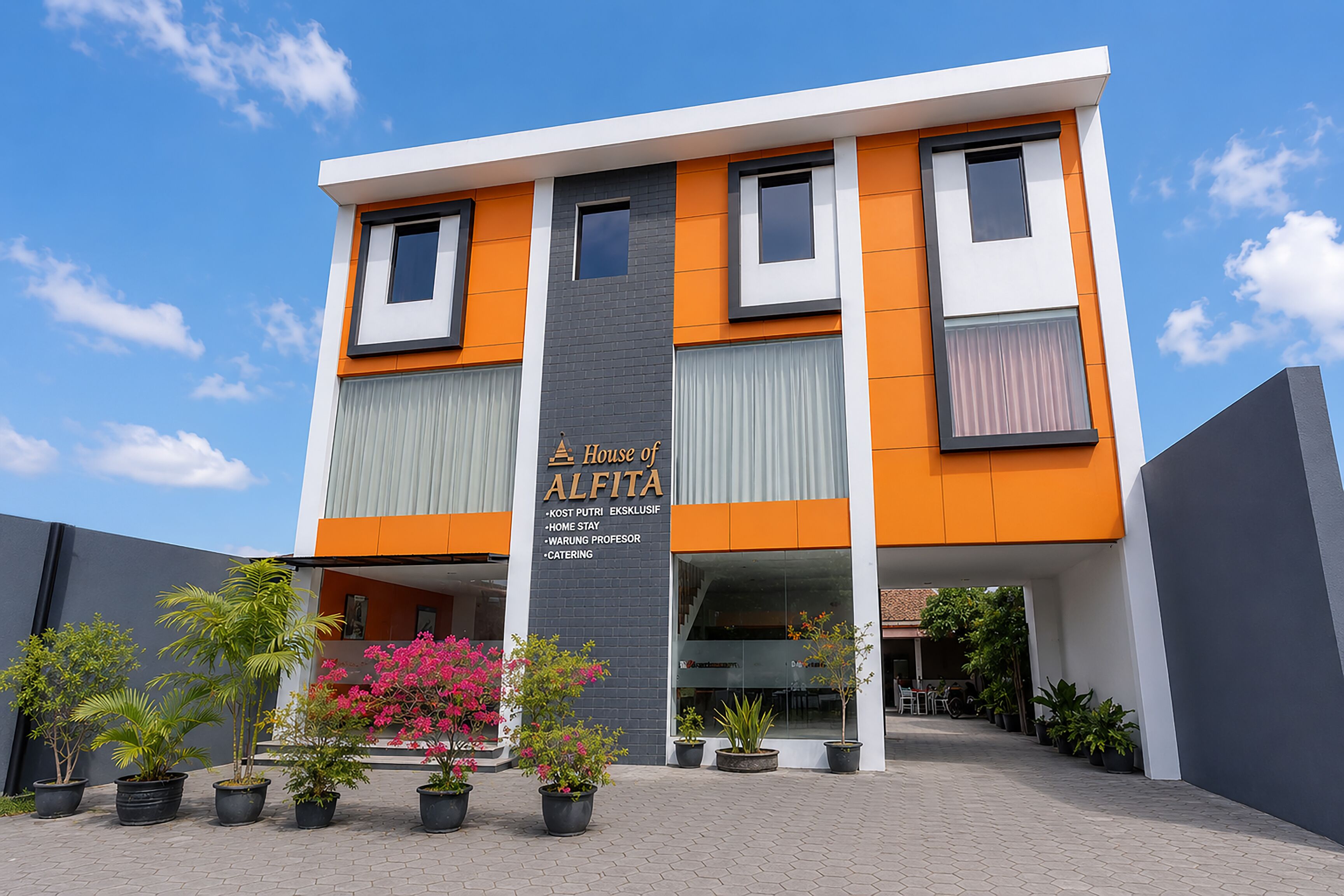 A modern building with a sign reading 'House of ALFITA' and a paved entrance area with potted plants.