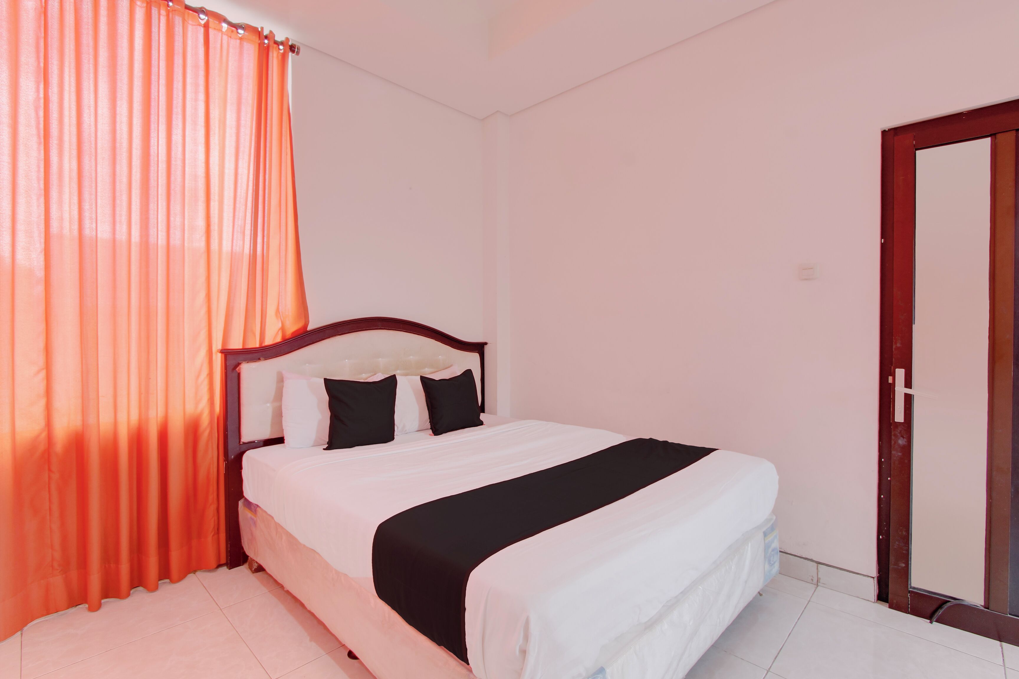 Un dormitorio con cama, cortinas, una puerta y suelo de baldosas.