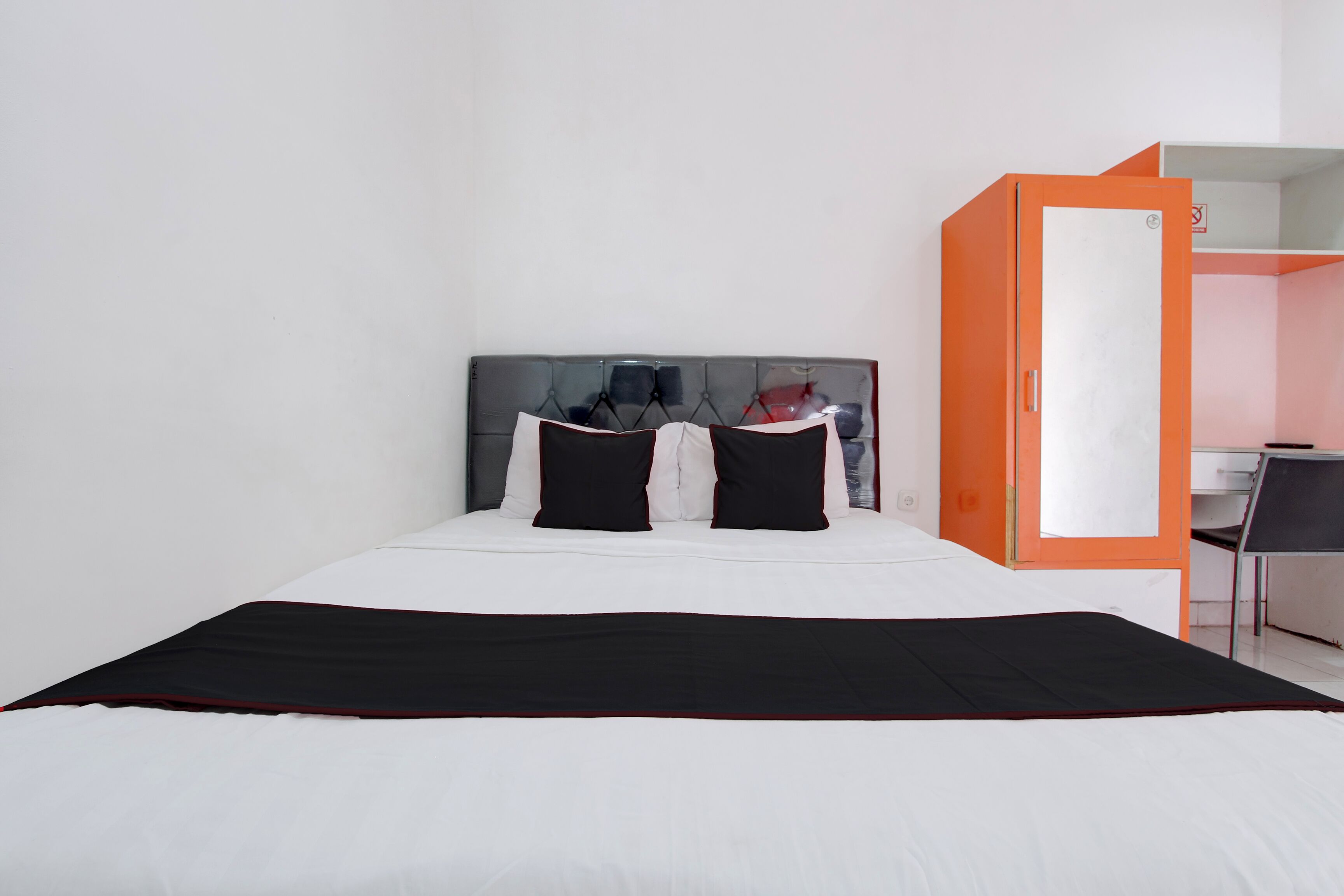 A hotel room with a bed, a wardrobe, and a desk.