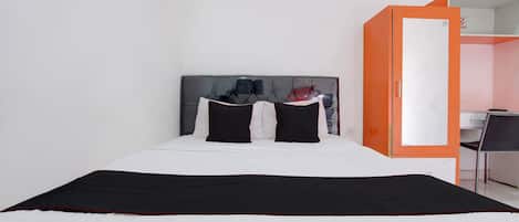 Una habitación de hotel con cama, armario y escritorio.